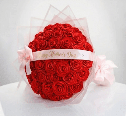 Red ribbon rose bouquet wrapped in pink paper with happy mothers day text on pink ribbon